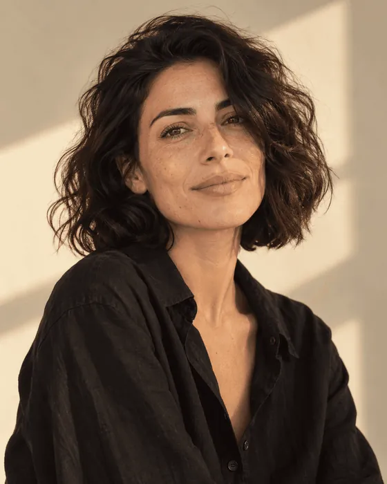 A woman with dark curls in warm afternoon light