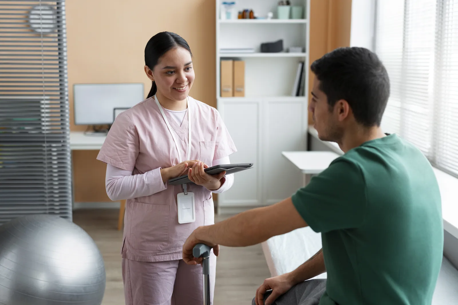 A physiotherapist with a tablet talking with a patient during a consultation