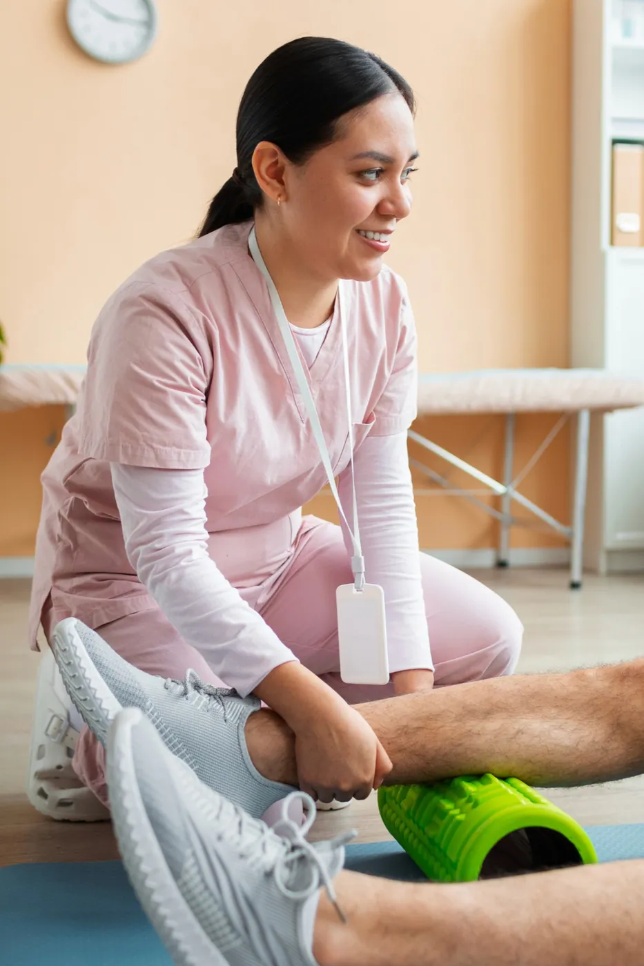 A physiotherapist helping a patient roll out his calf on a foam roller