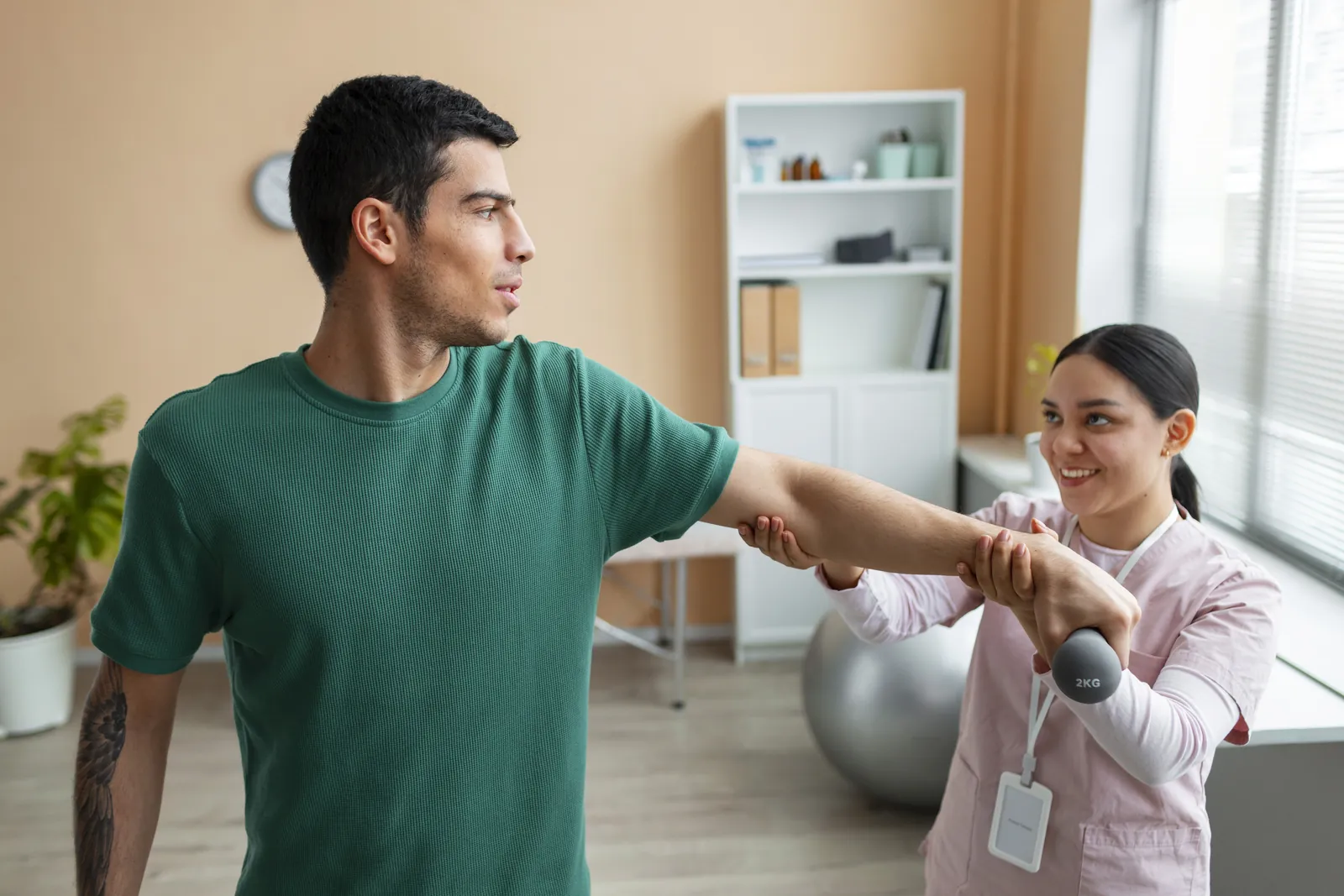 A physiotherapist guiding a patient through an arm exercise with a small weight