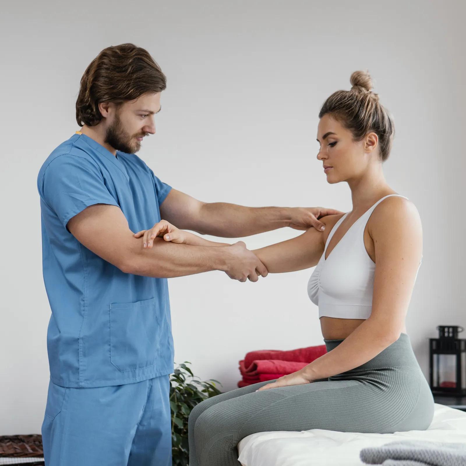 A physiotherapist stretching the arms of a seated patient to ease shoulder pain