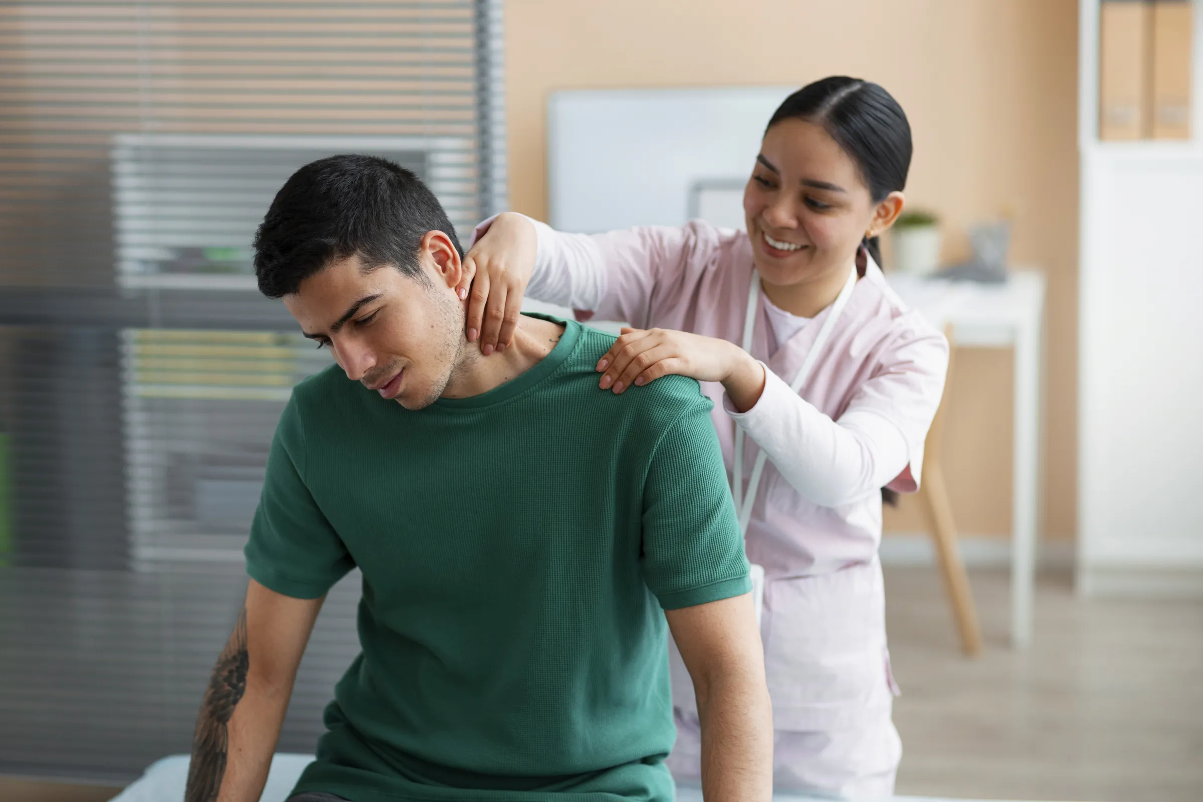 A smiling physiotherapist working on the shoulders of a seated patient