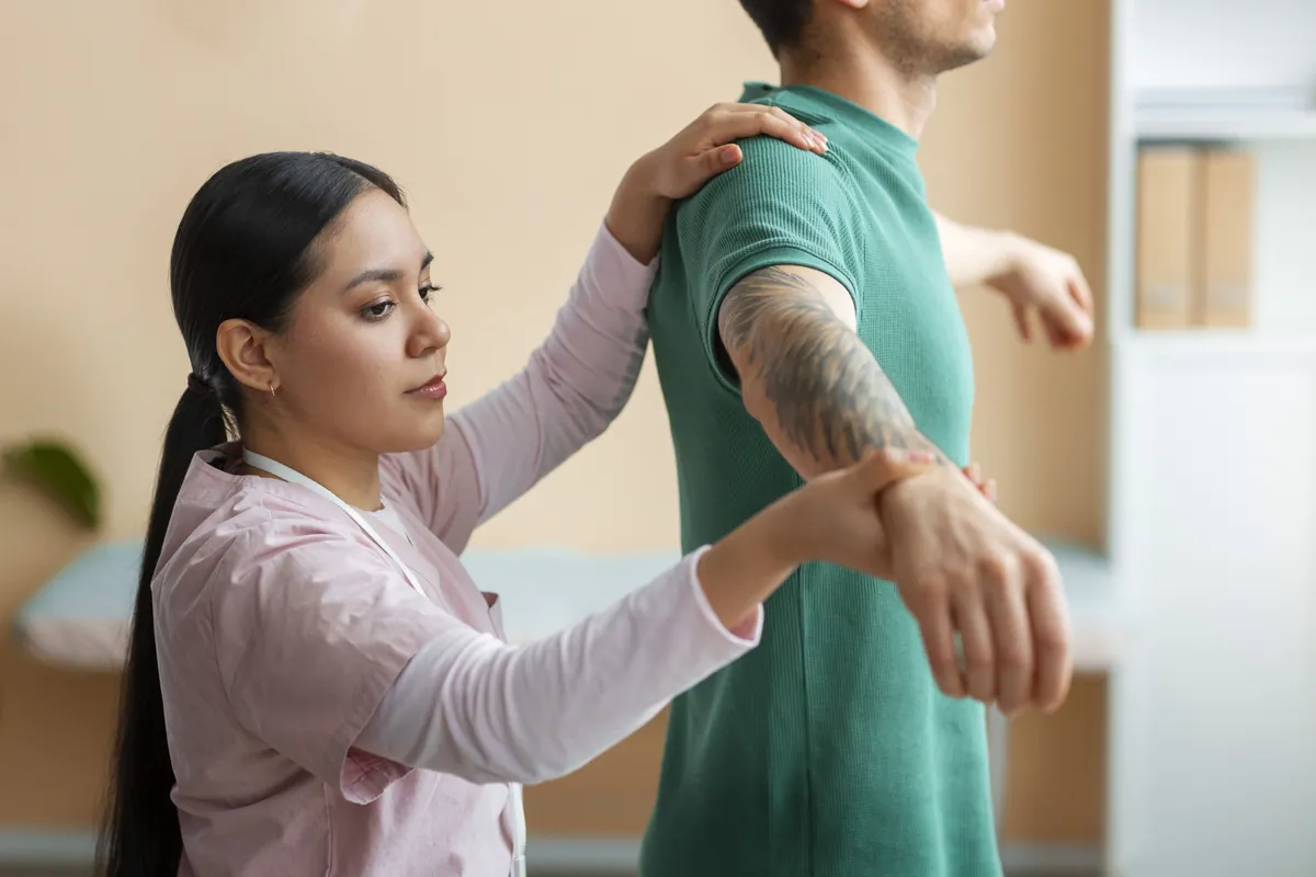 A physiotherapist assessing the shoulder movement of a standing patient