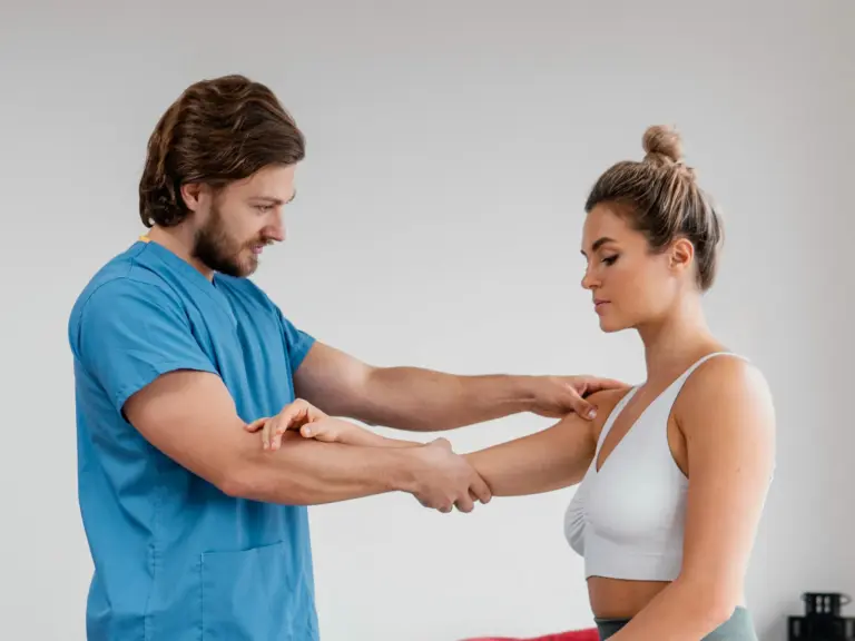 A physiotherapist guiding a patient’s arm through a shoulder mobility exercise