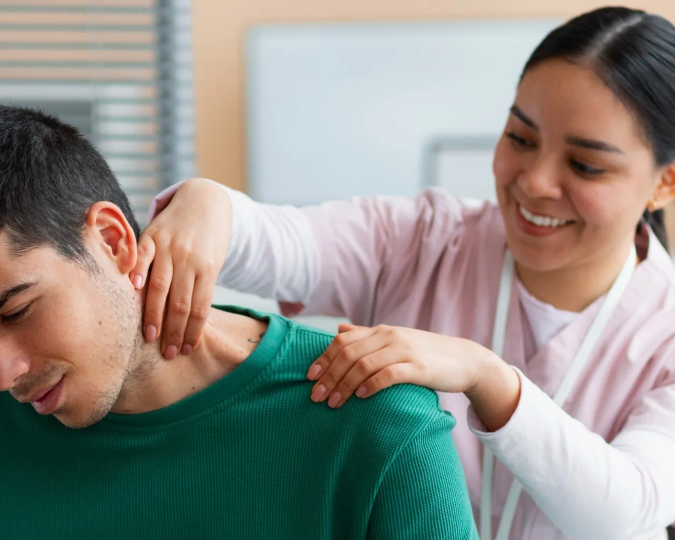 A chiropractor adjusting the upper back and shoulders of a seated patient