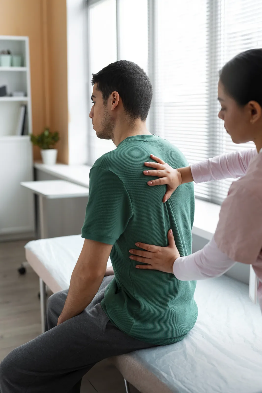 A physiotherapist placing her hands on a patient’s upper back