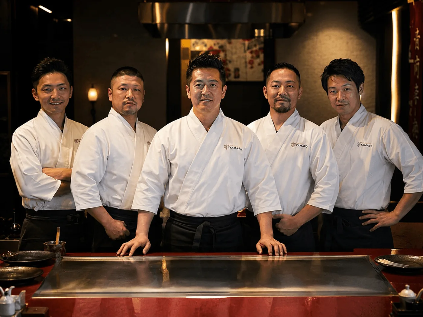 Six chefs in whites standing behind the counter
