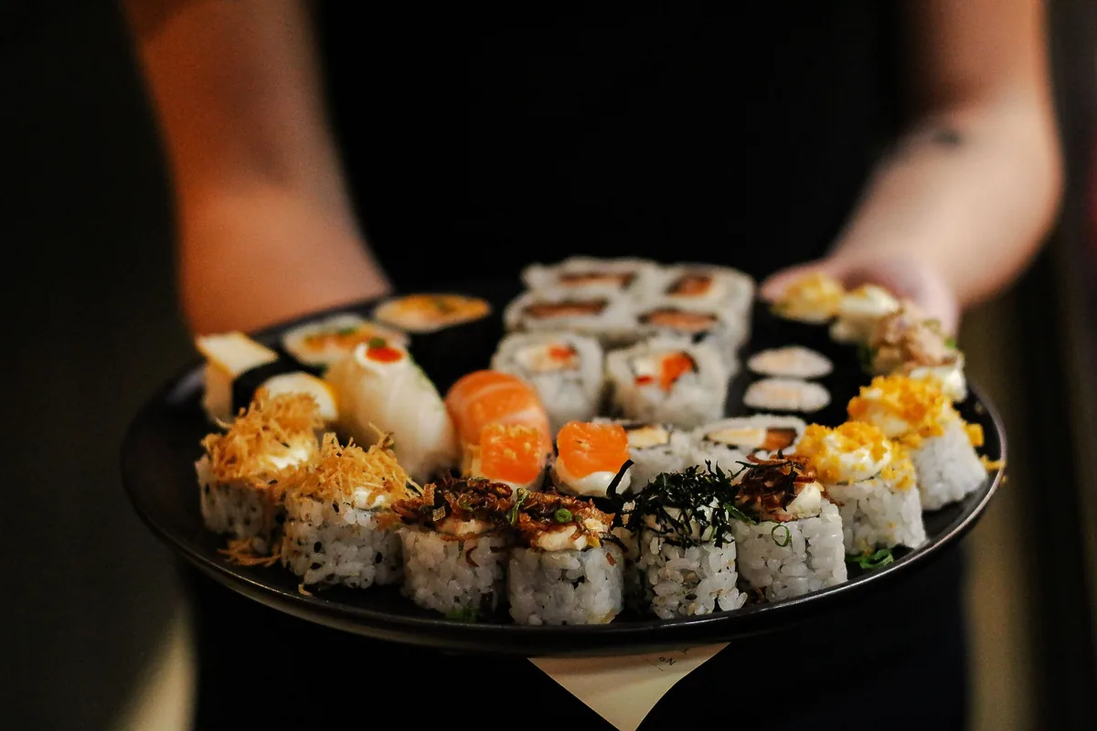 A platter of nigiri and rolls held out at the table