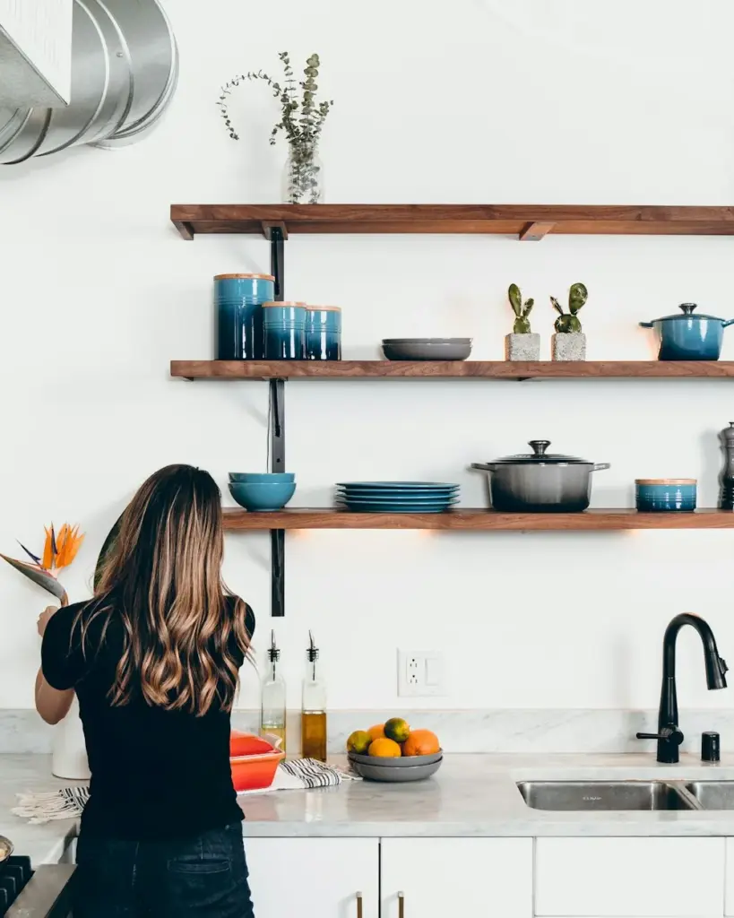 A woman tidying open kitchen shelves