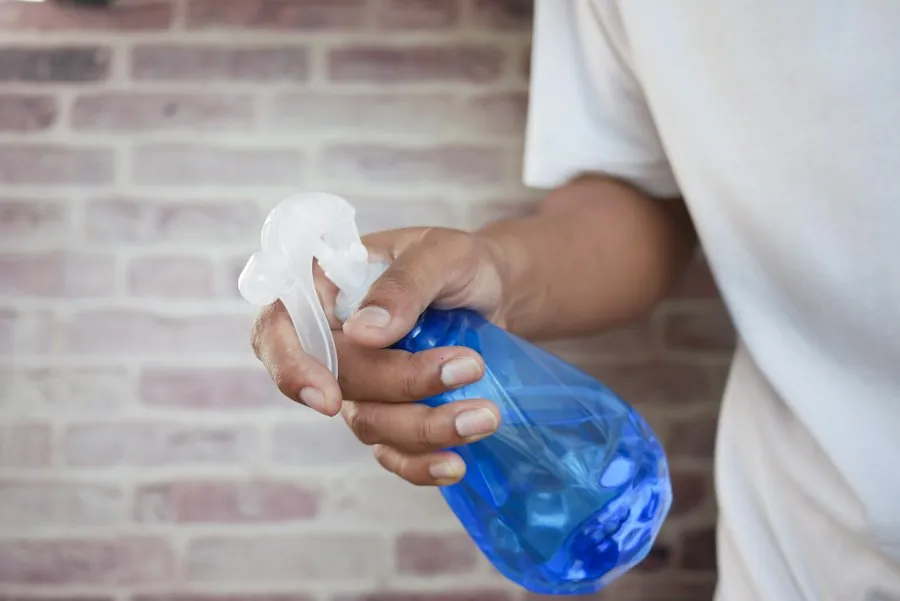 A hand holding a spray bottle ready to clean glass
