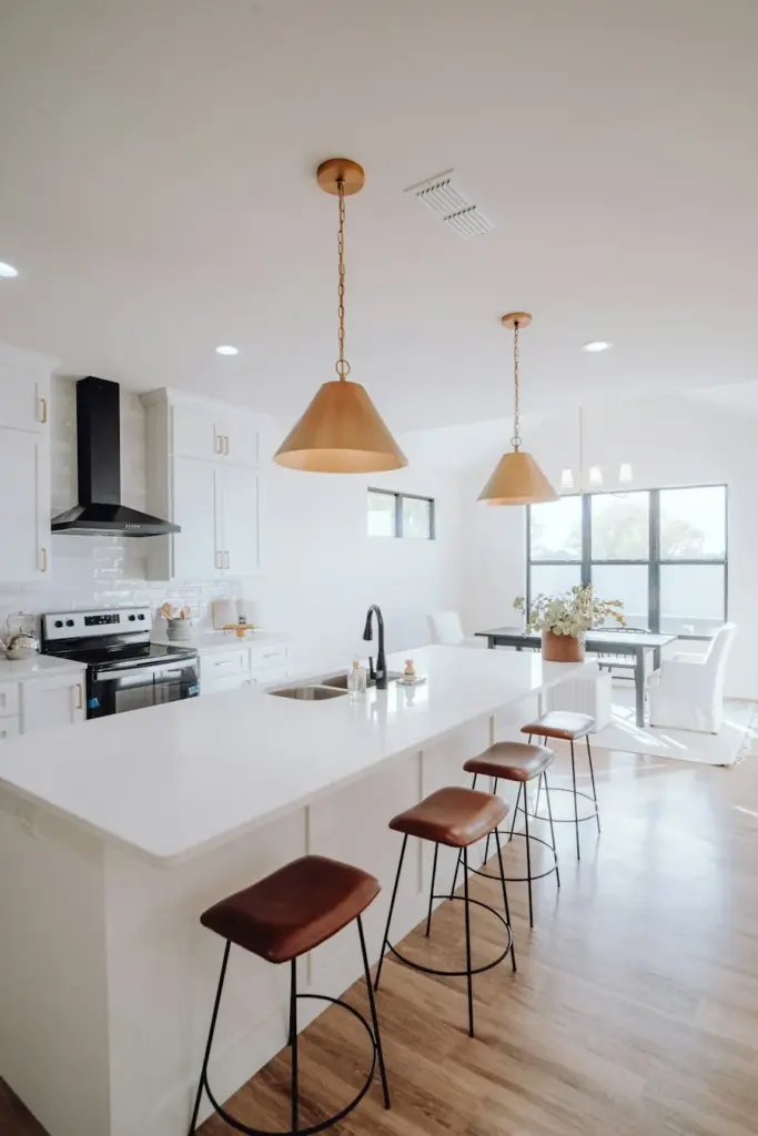 A spotless white kitchen with bar stools