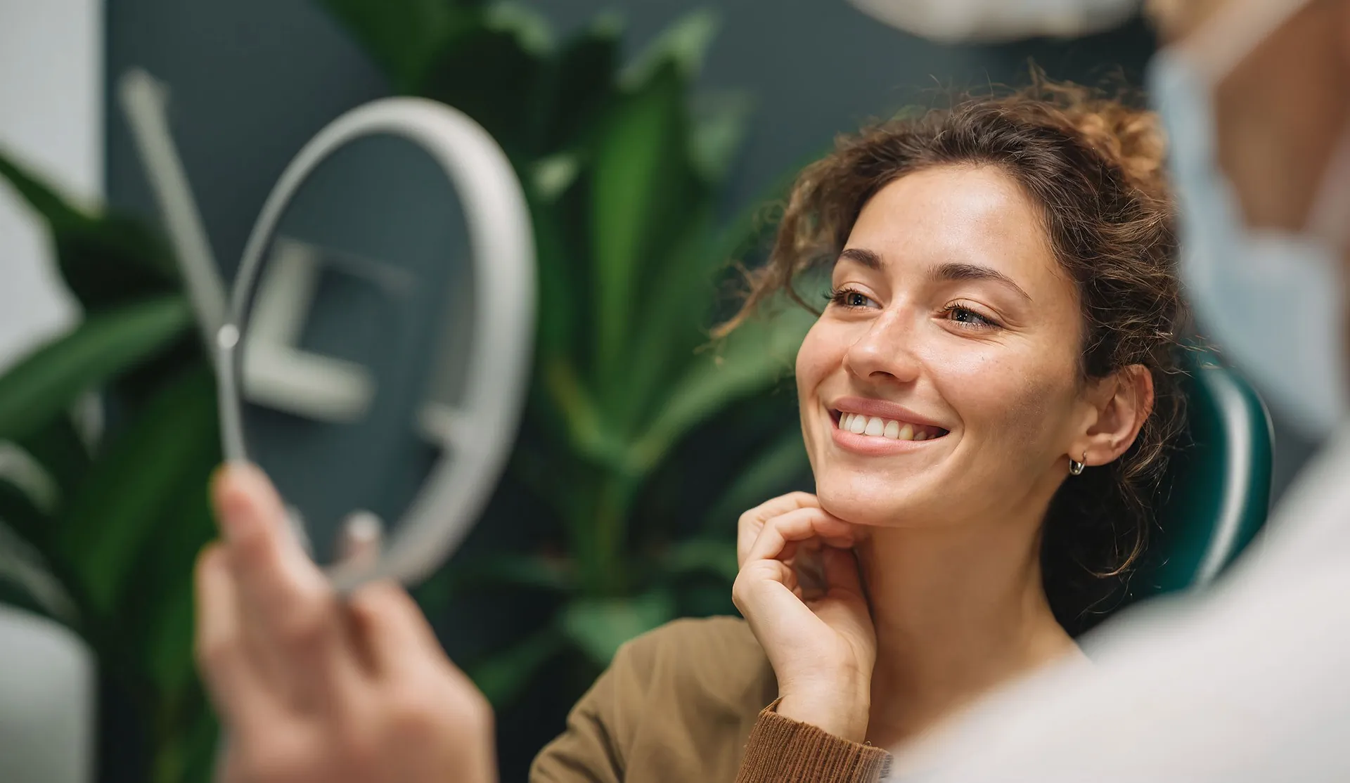 A woman looking in a dentist’s mirror and smiling