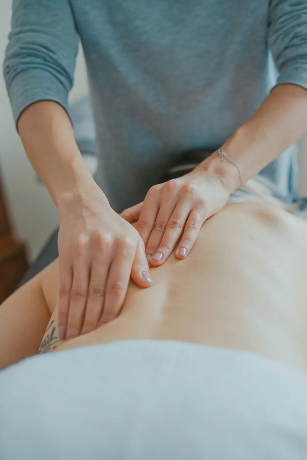 An osteopath’s hands pressing along a patient’s back