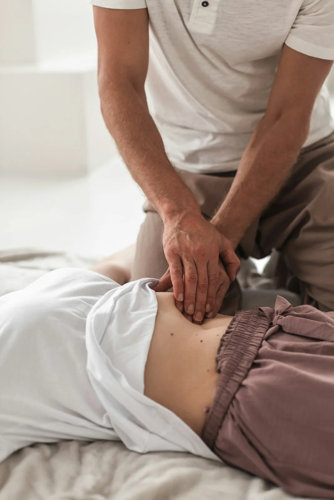 A physiotherapist working on a patient’s lower back on a treatment table