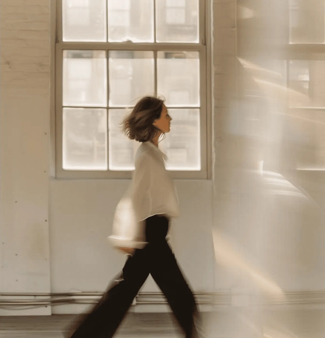 A woman walking past a sunlit window