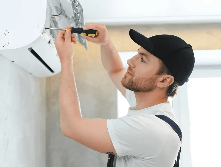 A technician adjusting a wall unit with a screwdriver