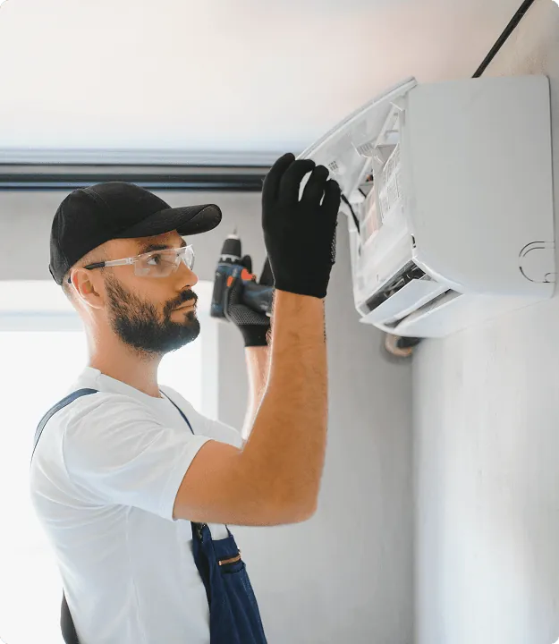 A technician in gloves opening a wall air conditioner
