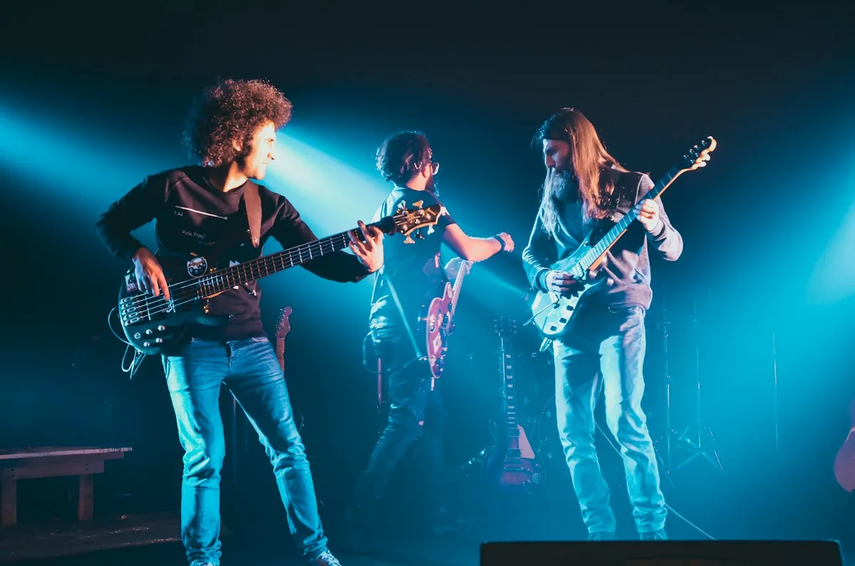Three young musicians playing guitar and bass on a lit stage