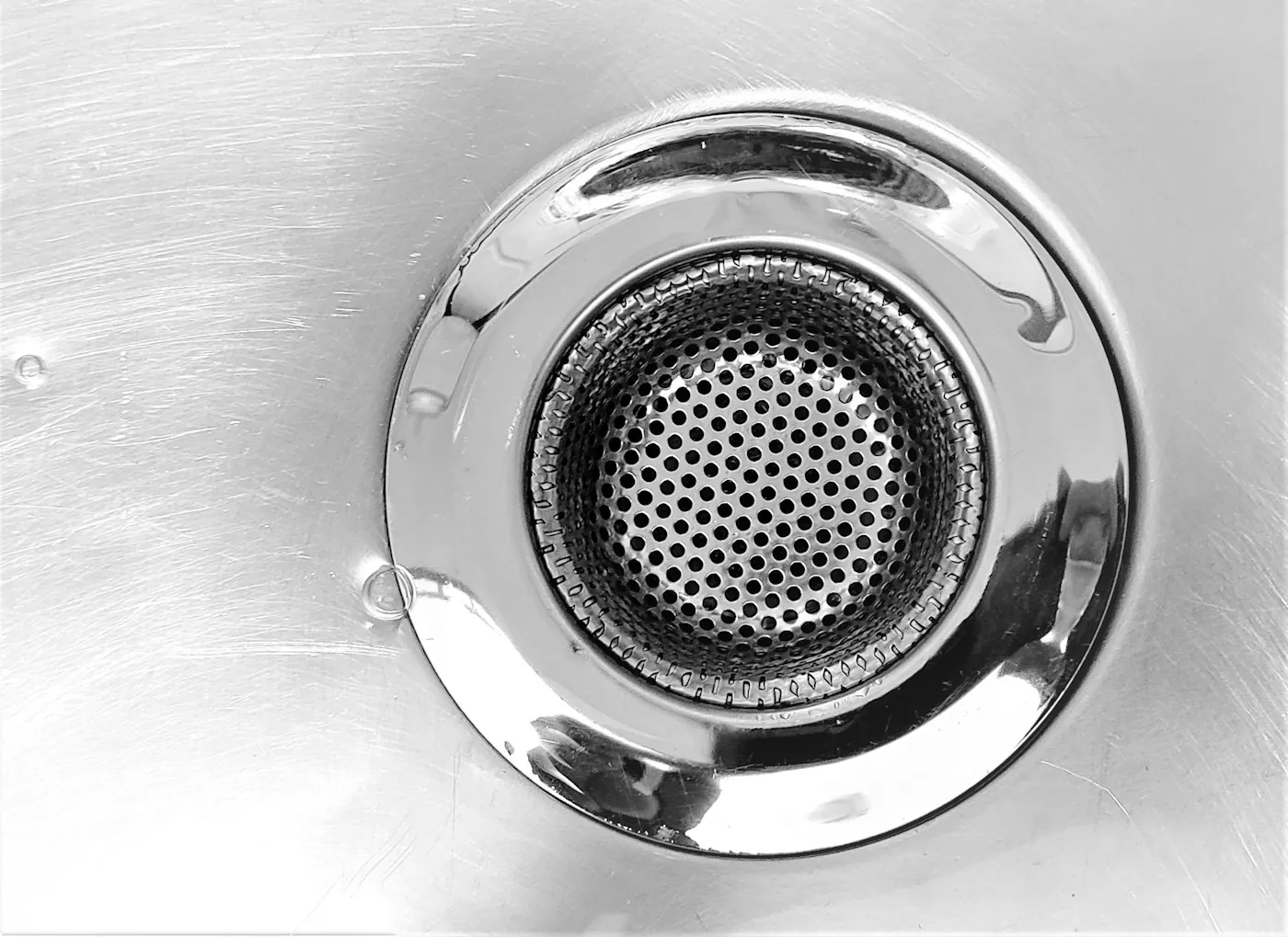 A close view of a stainless steel sink drain and its strainer