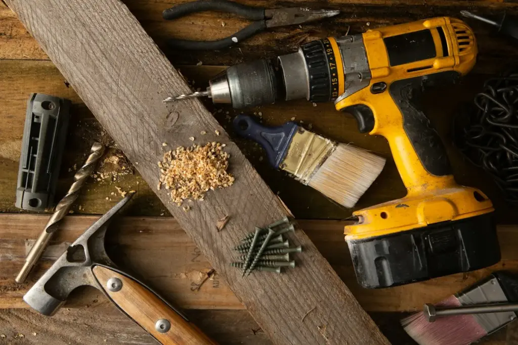 A cordless drill, a brush and screws on a timber board