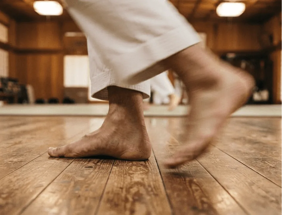 Bare feet stepping across the wooden dojo floor