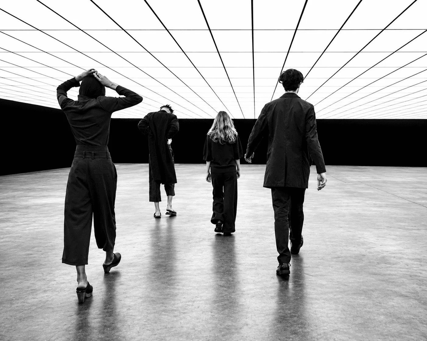 Four people walking across a lit hall