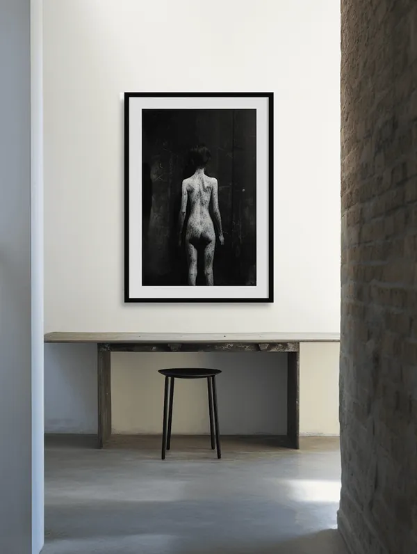 A framed photograph over a console and a stool