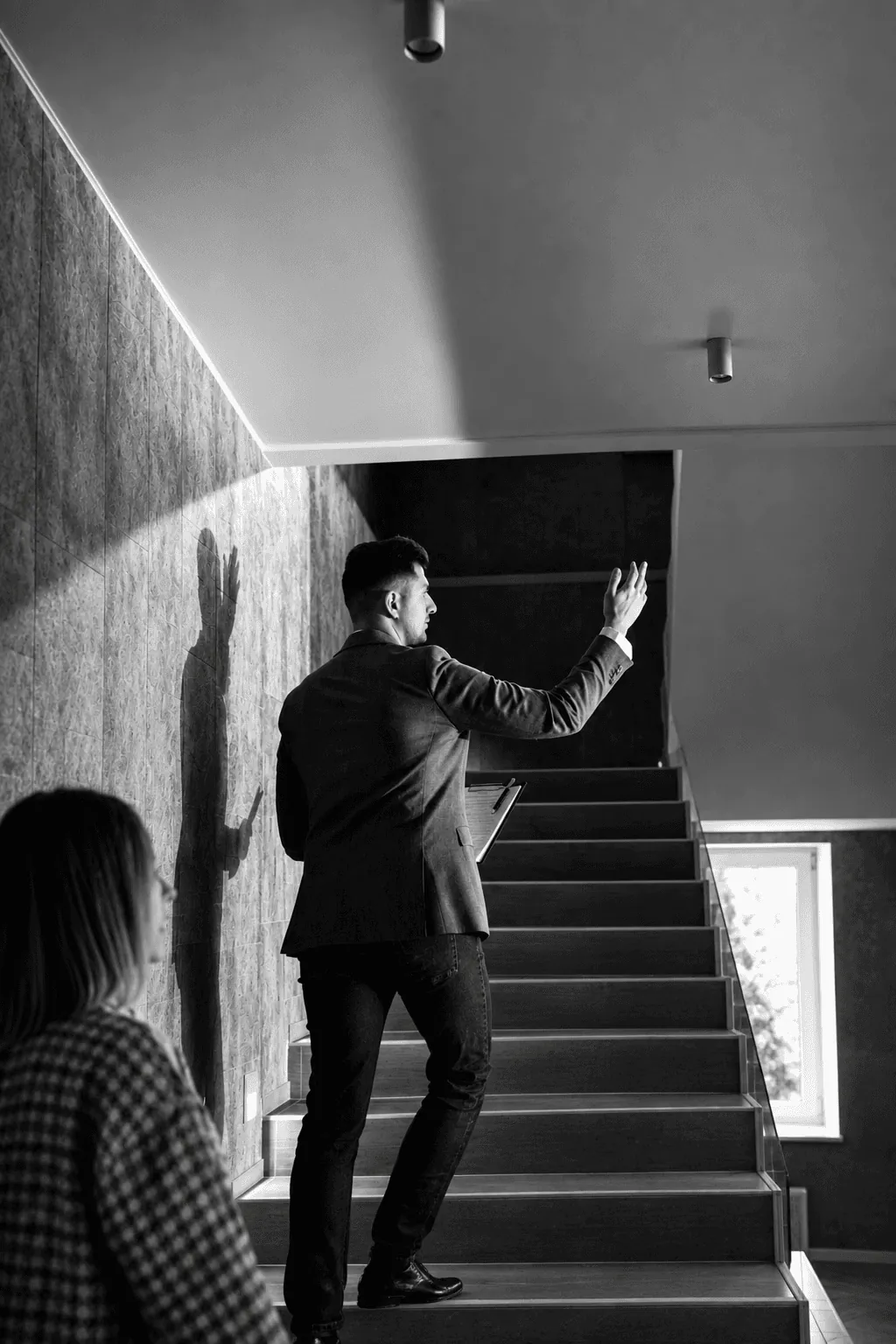 A man in a suit pointing up a stairwell