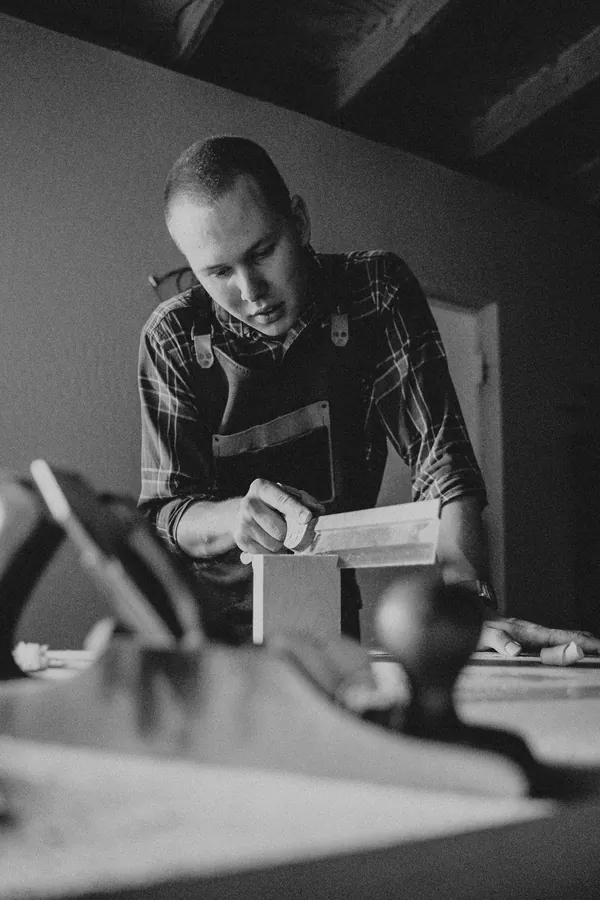 A carpenter measuring timber, in black and white