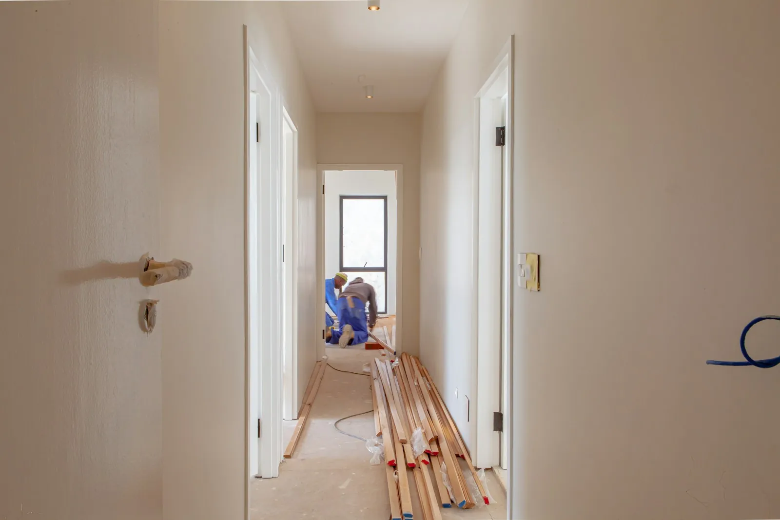 A worker fitting boards along a bright hallway