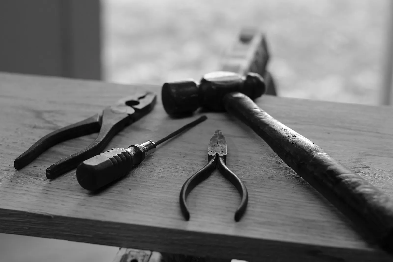 A hammer, pliers and screwdrivers on a wooden bench