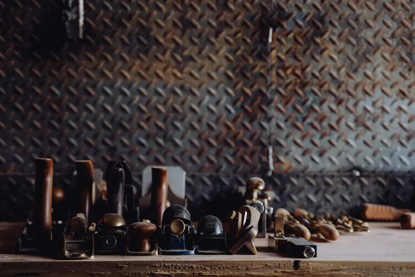 Old tools on a shelf against a patterned metal wall