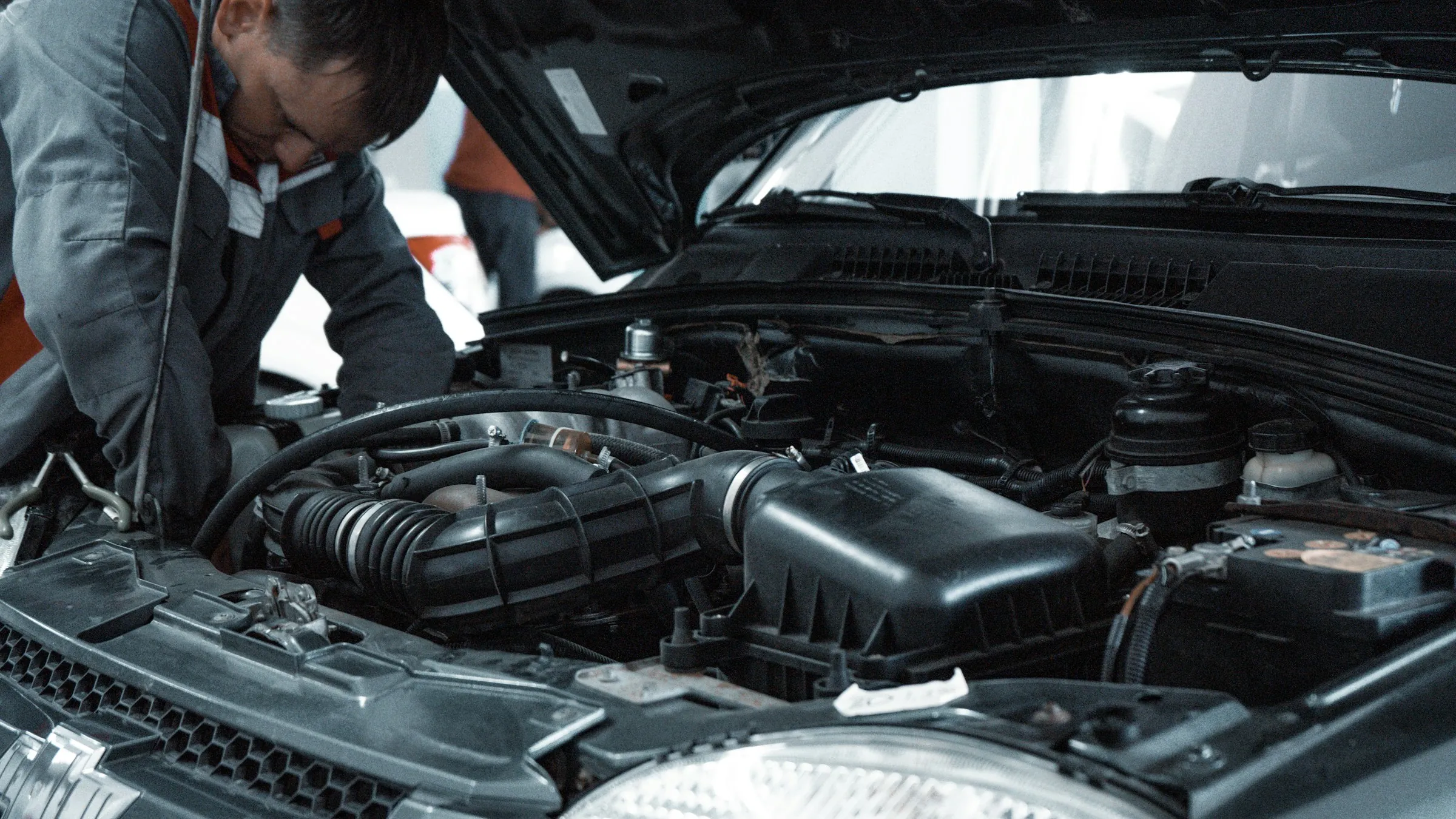 A mechanic leaning under an open bonnet