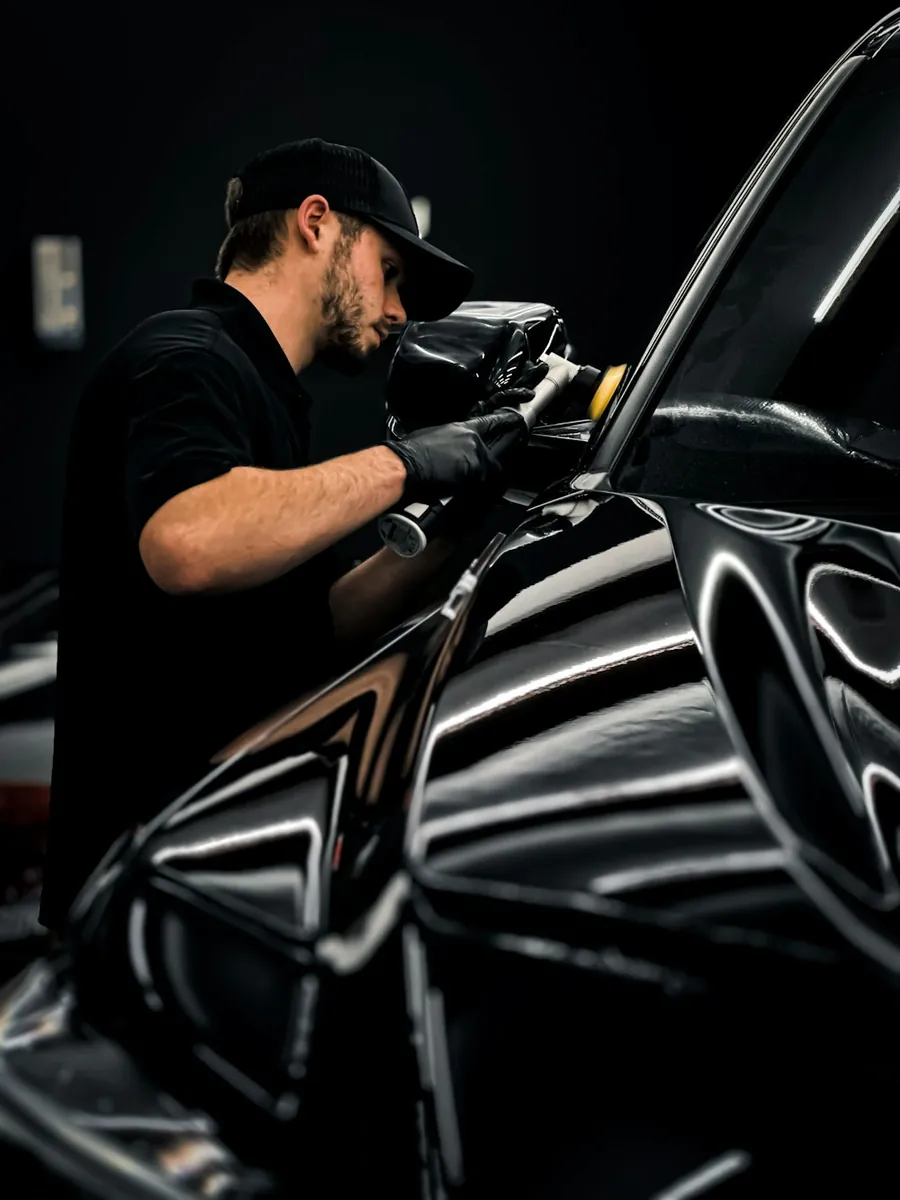 A detailer polishing the side of a black car