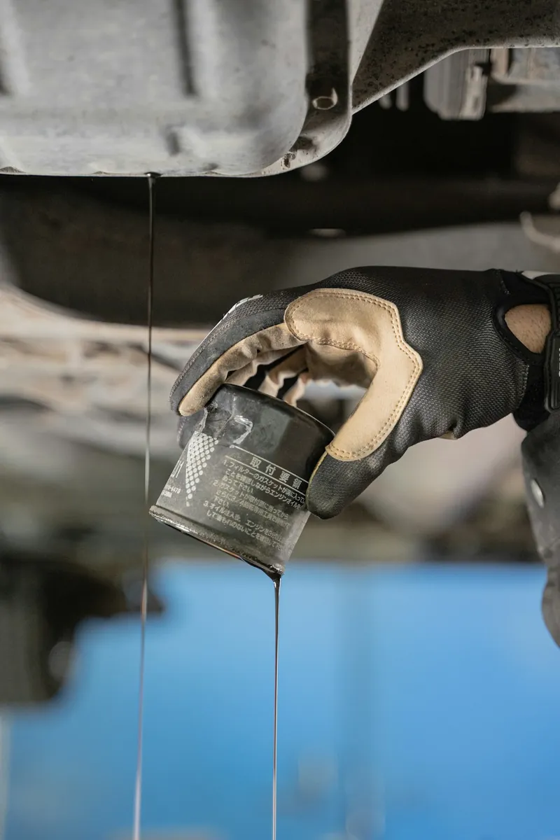 A gloved hand pouring fresh oil into an engine