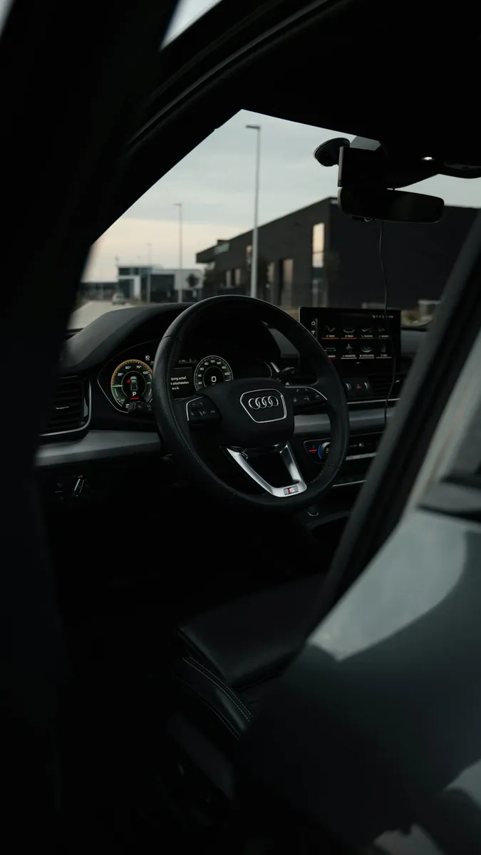 A steering wheel and dashboard seen through the open door