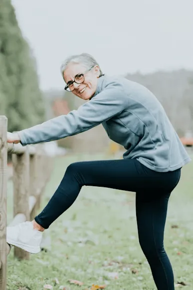An older man stretching his leg on a railing