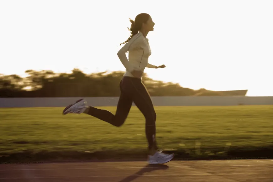 A woman running on a track at sunset