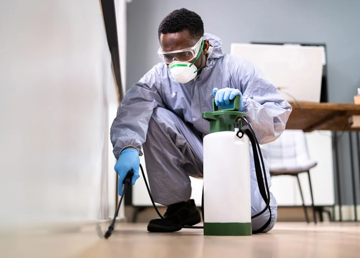A technician treating the edge of a kitchen floor