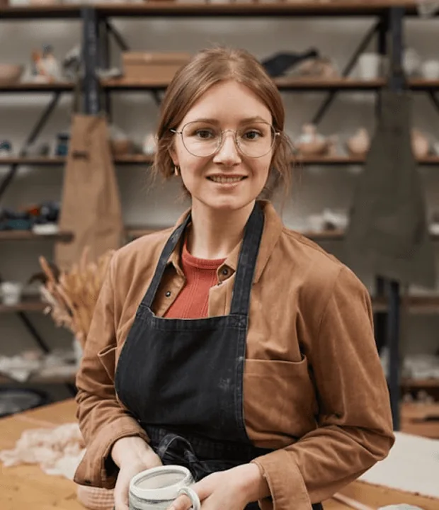 A shop owner in an apron smiling in her workshop