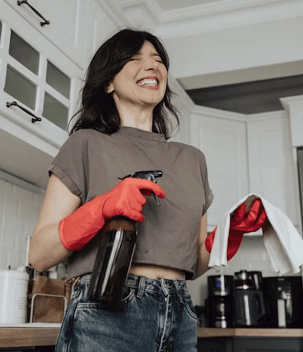 A laughing customer with a spray bottle in her kitchen