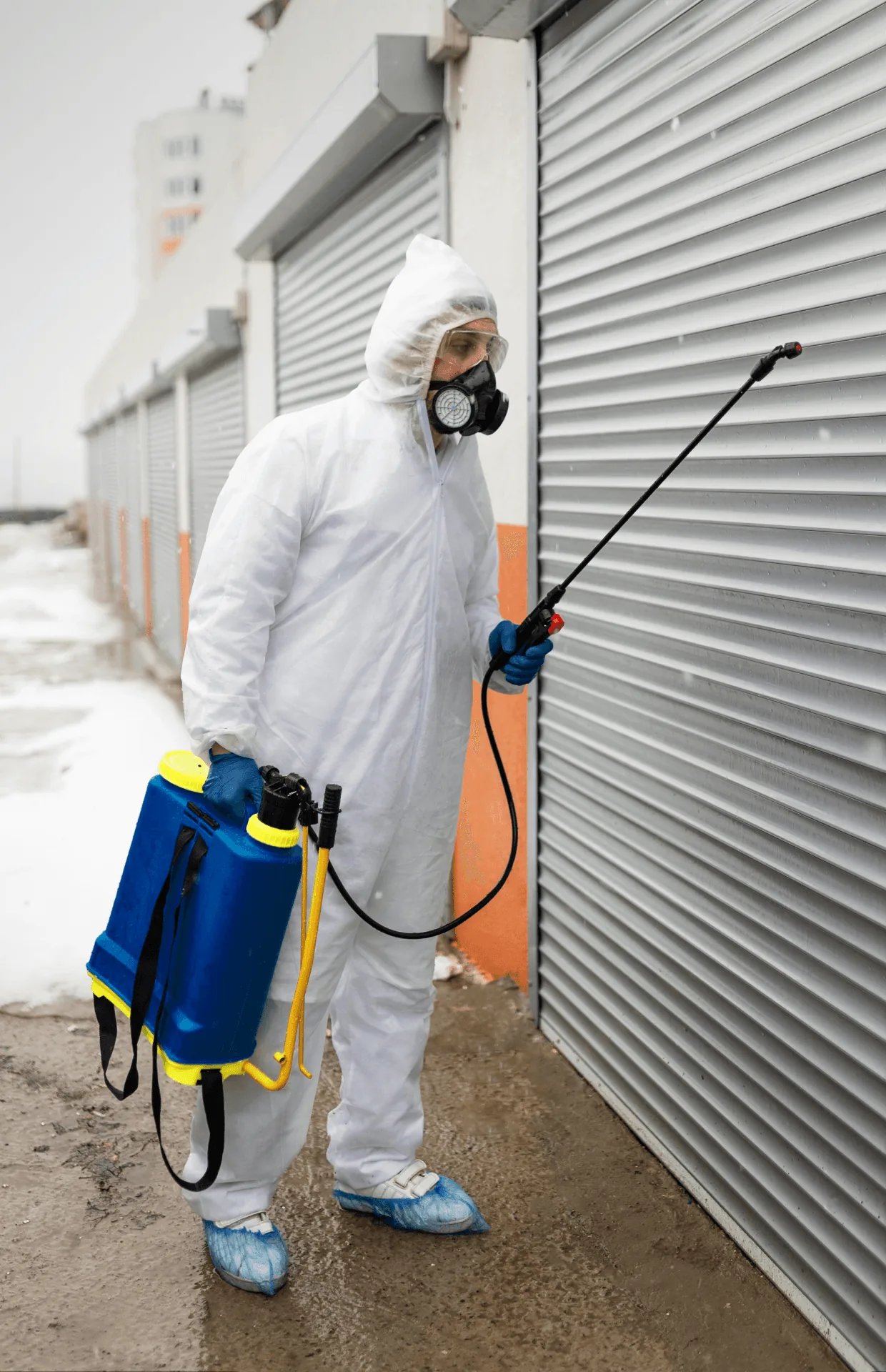 A technician with a backpack sprayer at a garage door