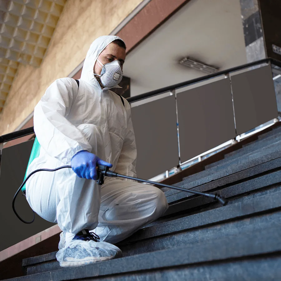 A technician in a protective suit treating a staircase