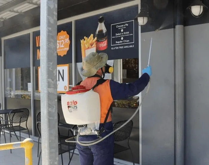 A technician spraying at a shop entrance for flies