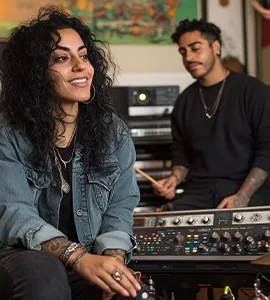 Two people laughing at a mixing desk in a recording studio