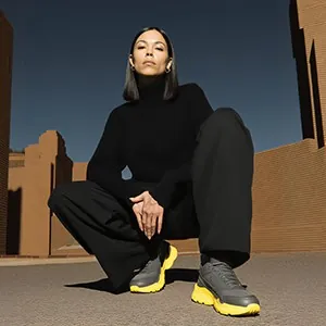 Crouching in black in front of a brick building