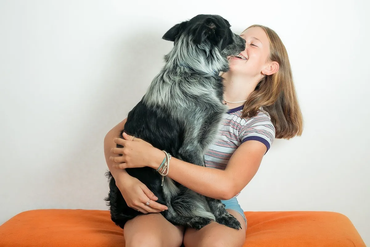 A girl hugging her fluffy black and white dog