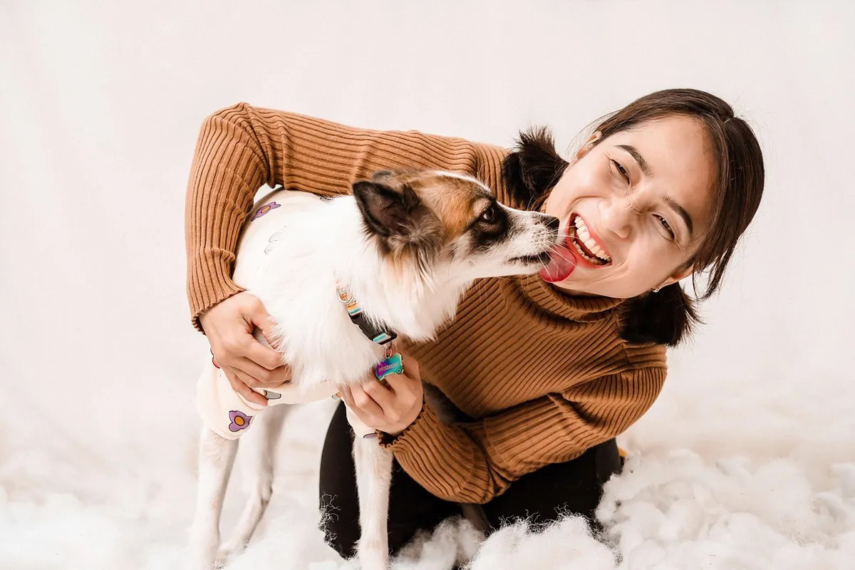 A smiling woman kissing her small dog