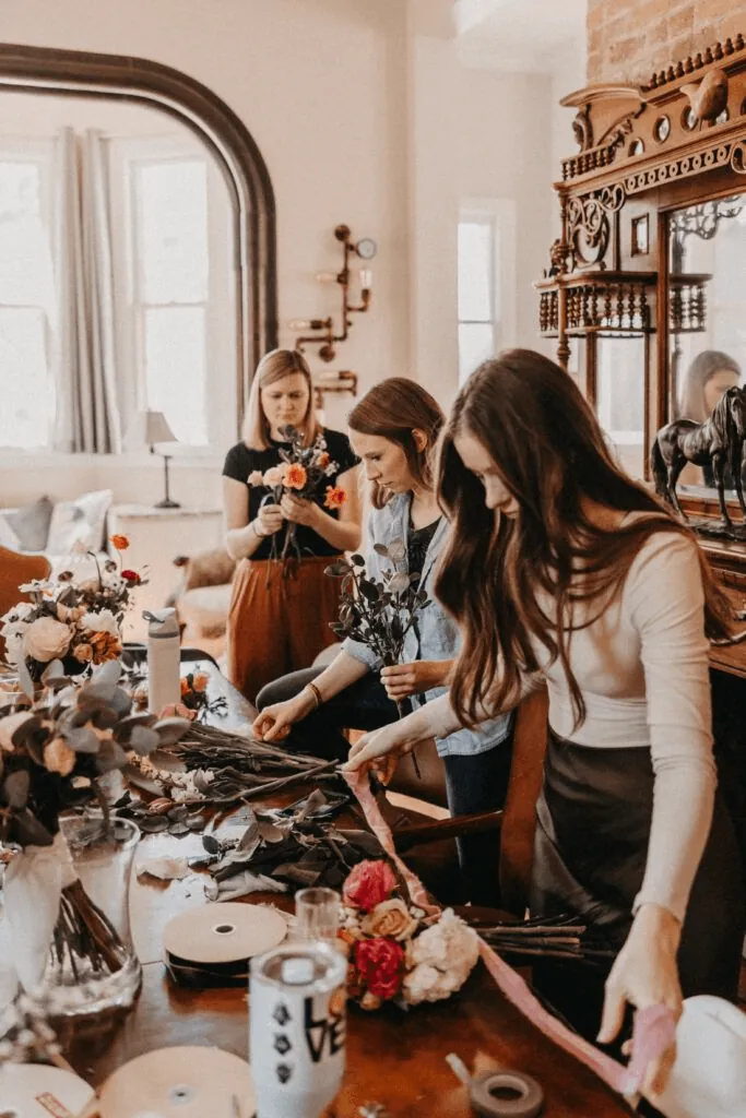 Florists preparing arrangements around a table full of flowers