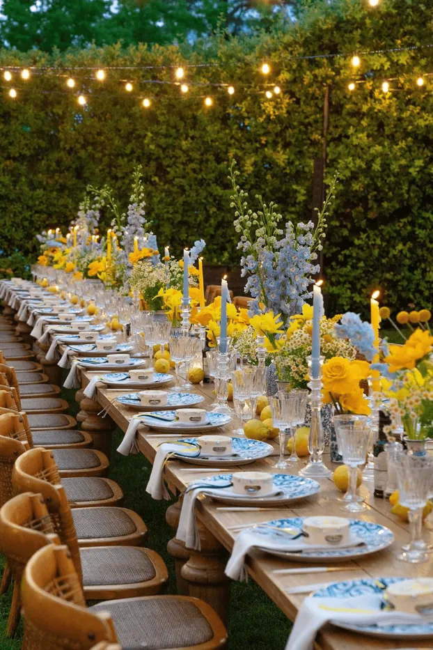 A long table with yellow flowers under string lights